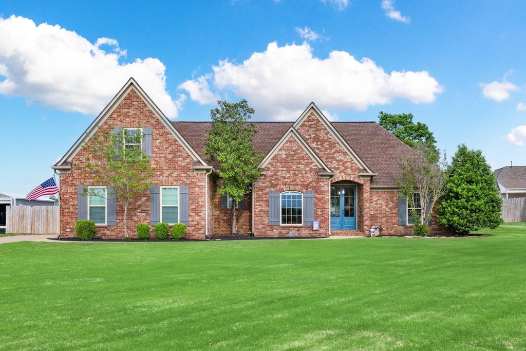 232 Rembert Dr, Atoka, TN 38004 - view of front of property with fence, roof with shingles, brick siding, and a front yard
