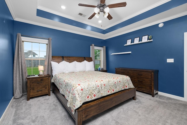 carpeted bedroom with ceiling fan, baseboards, a tray ceiling, visible vents, and ornamental molding