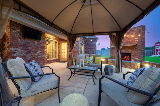 view of patio / terrace featuring fence, an outdoor living space with a fireplace, and a gazebo