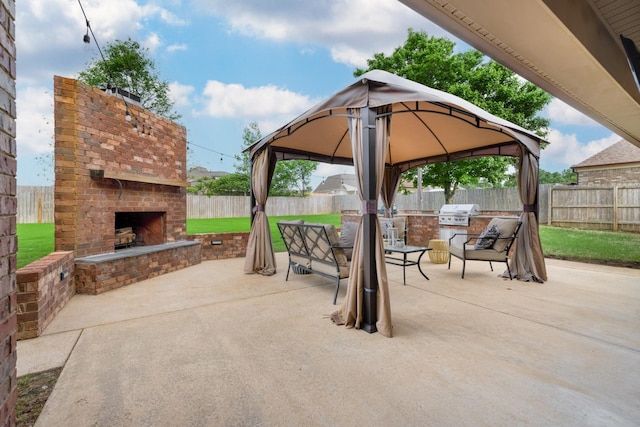 view of patio with area for grilling, a gazebo, a fenced backyard, and an outdoor brick fireplace