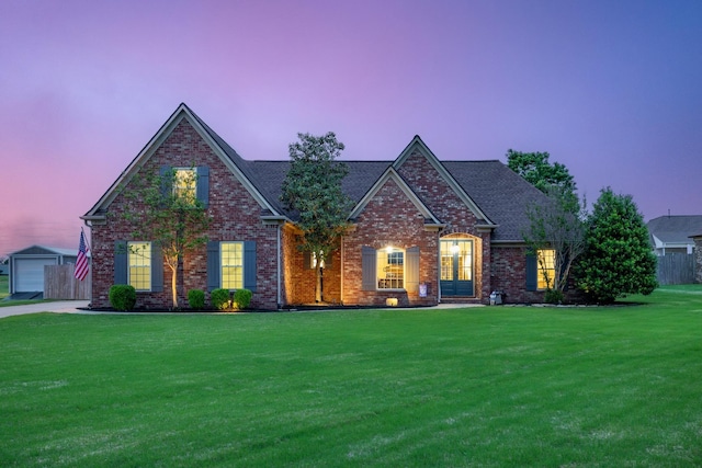 view of front of home with brick siding, an outdoor structure, a front lawn, and roof with shingles