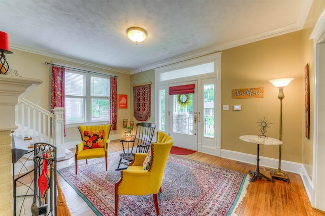 living area with crown molding, stairs, a wealth of natural light, and light wood-type flooring