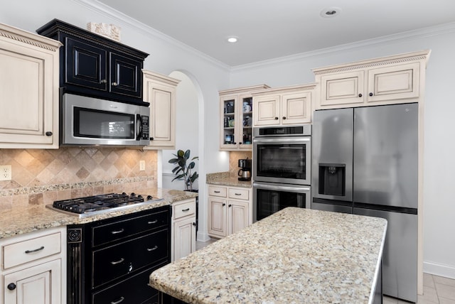 162 Harper St, Atoka, TN 38004 - kitchen featuring tasteful backsplash, dark cabinets, ornamental molding, stainless steel appliances, and cream cabinetry