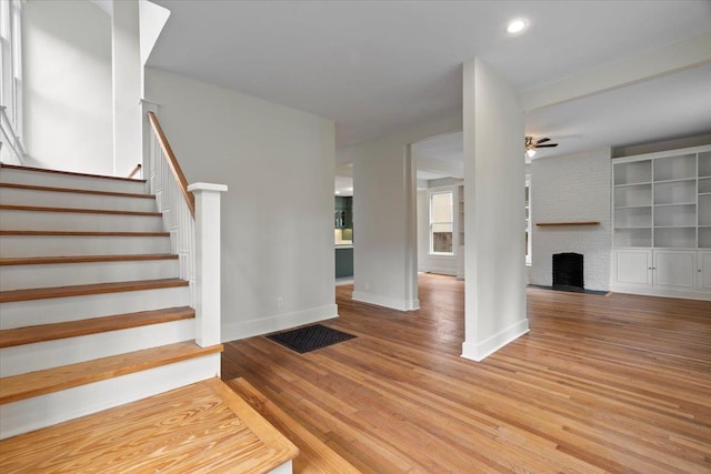 1682 Lawrence Ave, Memphis, TN 38112 - staircase with visible vents, a brick fireplace, wood finished floors, baseboards, and ceiling fan