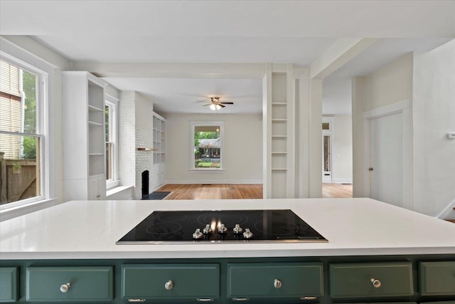 1682 Lawrence Ave, Memphis, TN 38112 - kitchen with light countertops, green cabinets, a brick fireplace, and black electric stovetop