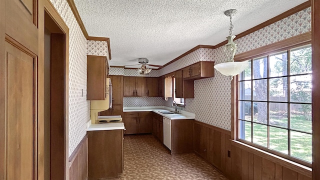 kitchen with a sink, crown molding, a textured ceiling, and wallpapered walls