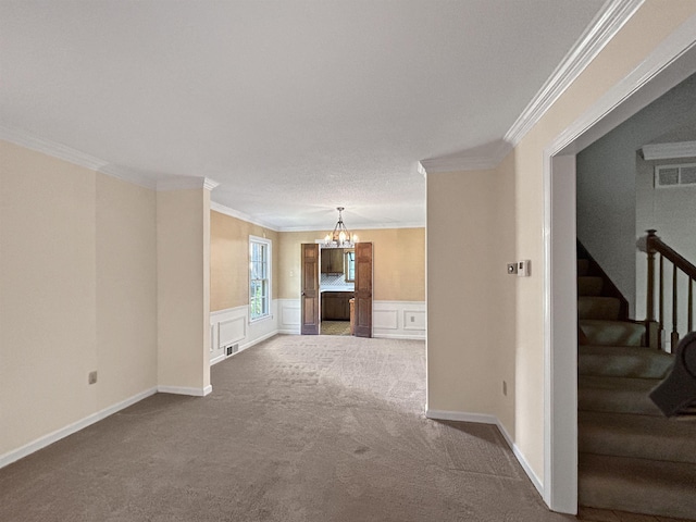 unfurnished living room with an inviting chandelier, carpet floors, crown molding, visible vents, and stairway