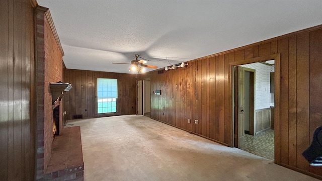 unfurnished living room with a fireplace, ceiling fan, and wooden walls