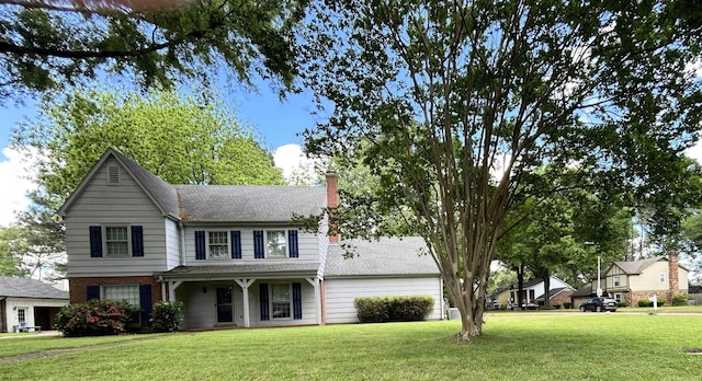 traditional home featuring a shingled roof, a chimney, and a front yard