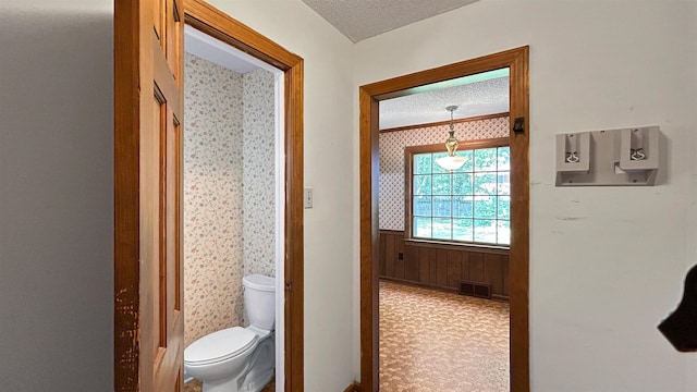 bathroom featuring toilet, a textured ceiling, a wainscoted wall, and visible vents
