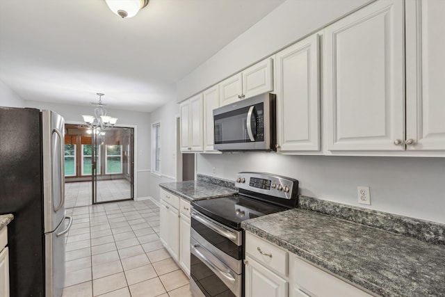kitchen featuring dark countertops, light tile patterned floors, an inviting chandelier, stainless steel appliances, and white cabinetry