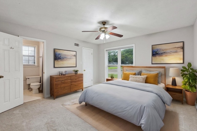 bedroom featuring visible vents, connected bathroom, light carpet, and multiple windows