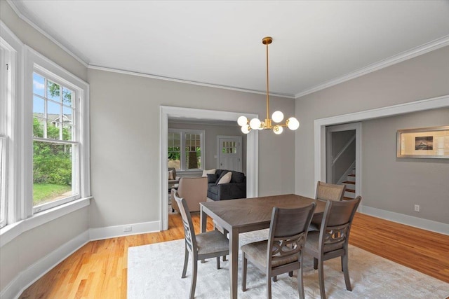 dining room with light wood-style floors, baseboards, ornamental molding, and a notable chandelier