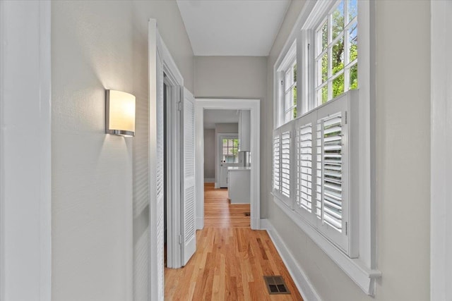 corridor with visible vents, baseboards, and light wood-type flooring