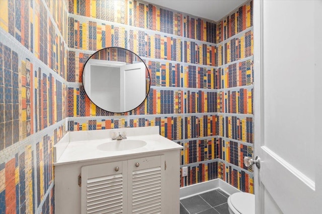 half bath featuring vanity, tile patterned flooring, wallpapered walls, and toilet
