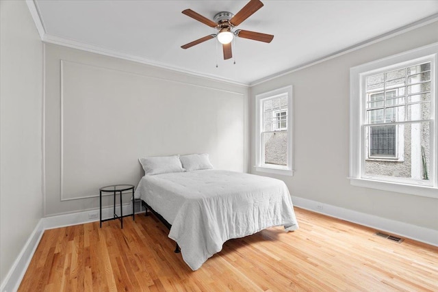 bedroom featuring crown molding, baseboards, visible vents, and wood finished floors