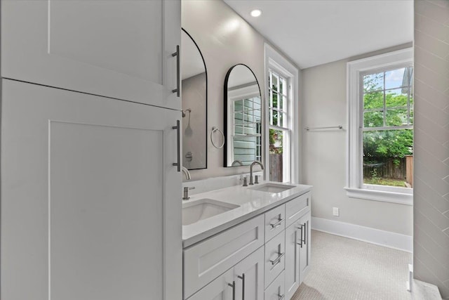 full bathroom with baseboards, a sink, double vanity, and recessed lighting