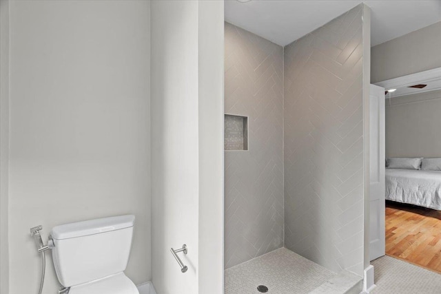 ensuite bathroom with a stall shower, ensuite bath, toilet, and wood finished floors