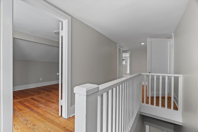 hallway with baseboards, recessed lighting, wood finished floors, and an upstairs landing