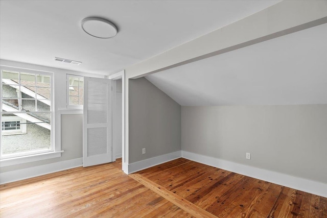 additional living space featuring baseboards, lofted ceiling, light wood-type flooring, and visible vents