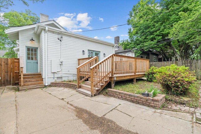 rear view of house with a chimney, a wooden deck, fence, a patio, and entry steps