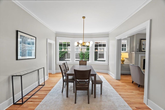 dining space with baseboards, a notable chandelier, ornamental molding, and light wood-style floors