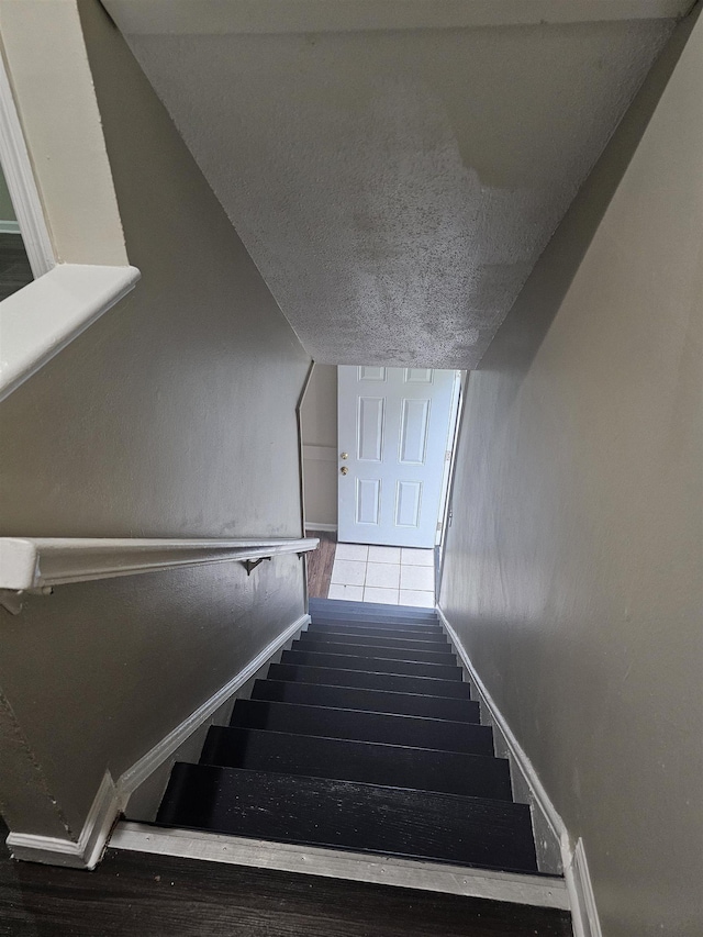 staircase featuring baseboards and a textured ceiling