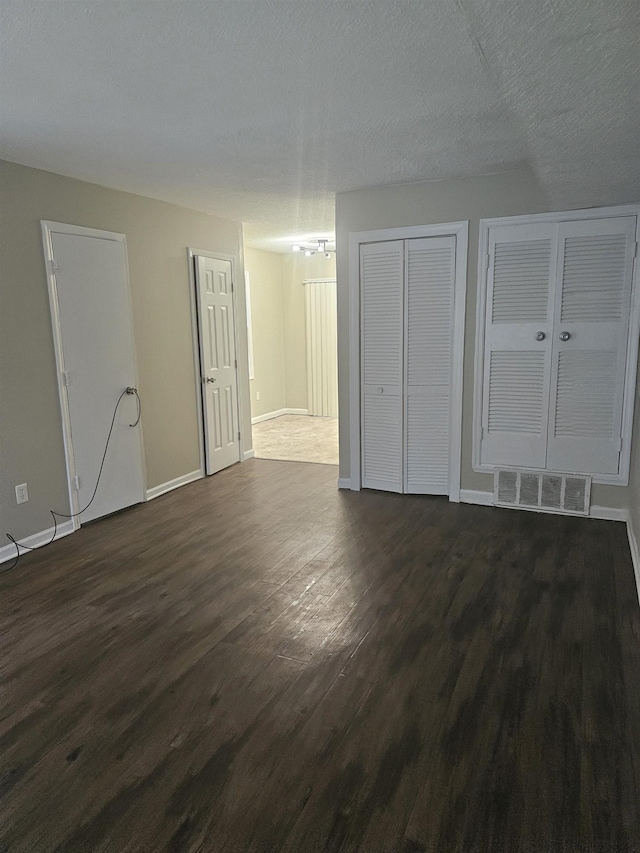 interior space featuring visible vents, baseboards, dark wood-style floors, a chandelier, and multiple closets