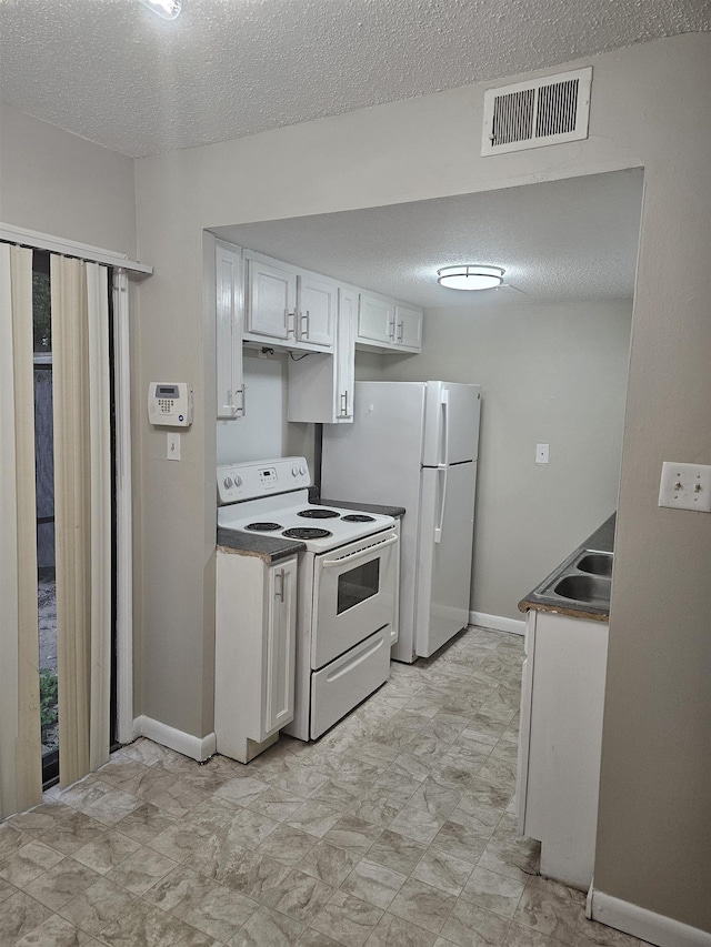 kitchen with visible vents, a sink, a textured ceiling, and white appliances