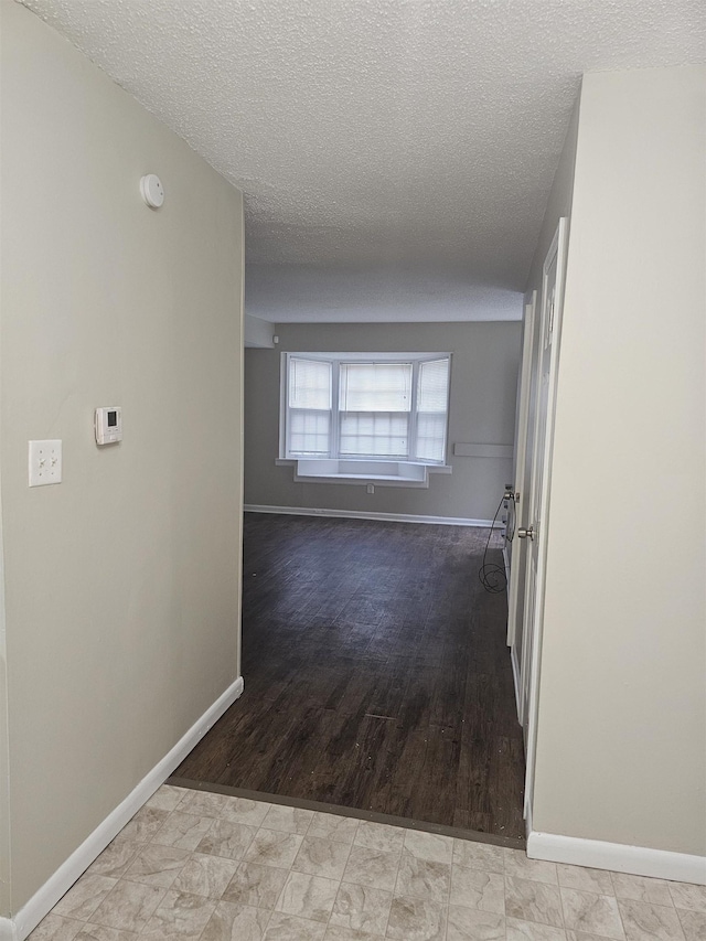 hall with baseboards and a textured ceiling