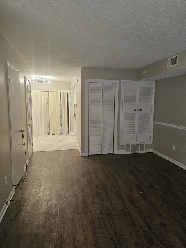 interior space featuring a textured ceiling, visible vents, and dark wood finished floors