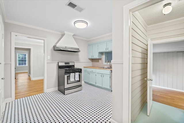 kitchen with blue cabinets, visible vents, gas range, a sink, and custom exhaust hood