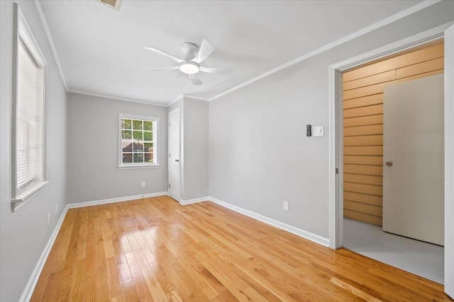unfurnished room with a ceiling fan, baseboards, ornamental molding, and light wood-type flooring
