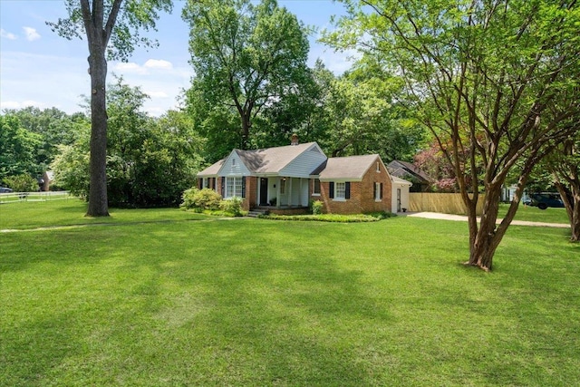 ranch-style house featuring fence, a chimney, a front lawn, and brick siding