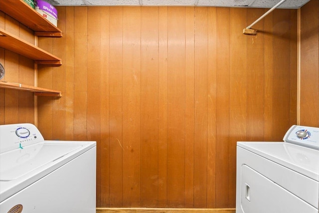 laundry room with washer and dryer, wooden walls, and laundry area