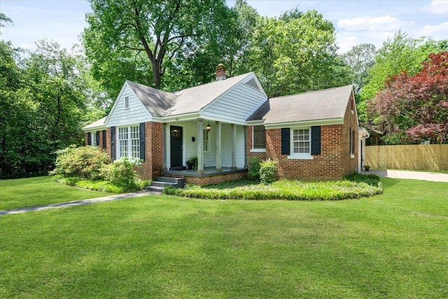 ranch-style home with a porch, brick siding, fence, and a front lawn