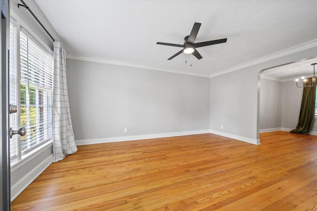 empty room featuring crown molding, baseboards, ceiling fan with notable chandelier, and light wood-type flooring