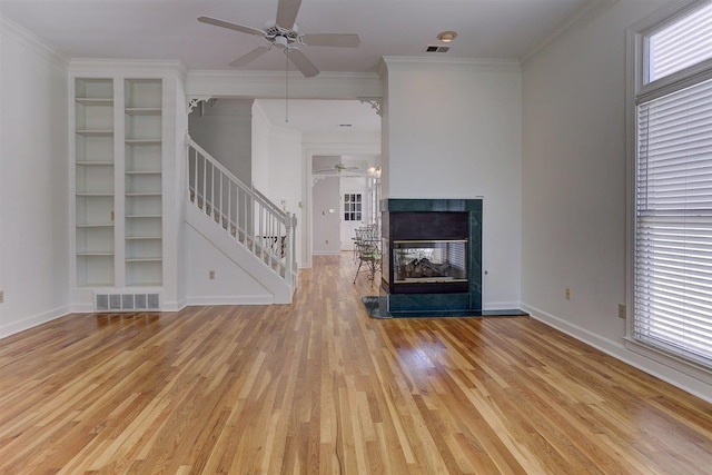unfurnished living room with visible vents, light wood-style flooring, stairs, and ceiling fan