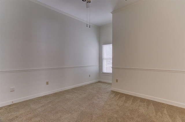 empty room featuring crown molding, carpet, and baseboards