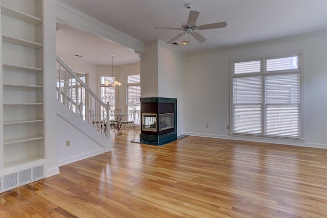 unfurnished living room with visible vents, built in features, baseboards, stairs, and light wood-style flooring