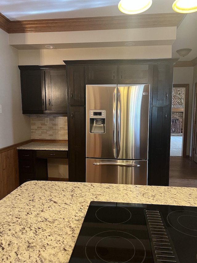 kitchen with crown molding, backsplash, light stone countertops, and stainless steel fridge with ice dispenser