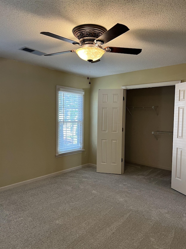 unfurnished bedroom with a closet, a ceiling fan, baseboards, a textured ceiling, and carpet flooring