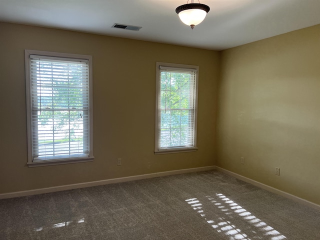 carpeted empty room featuring baseboards and visible vents
