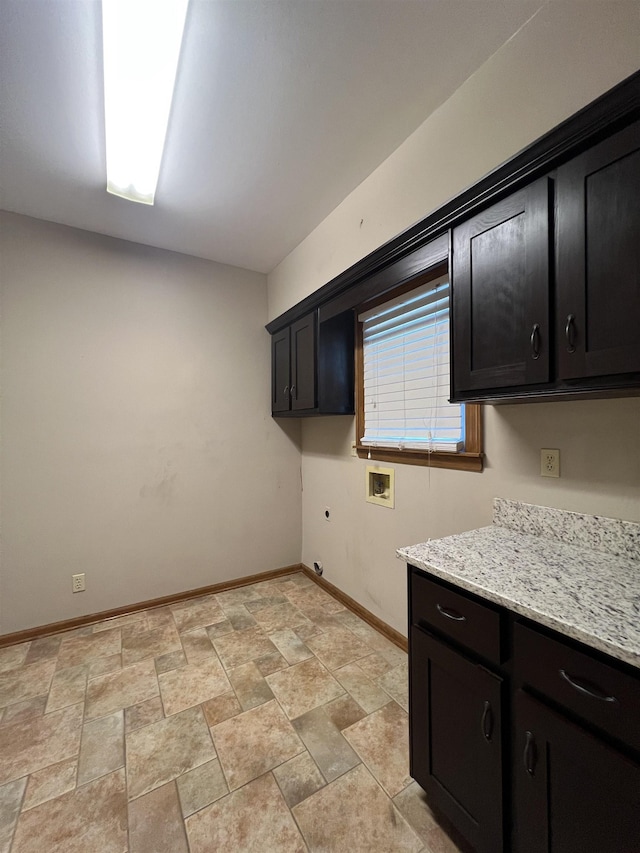 interior space with dark cabinets, baseboards, stone finish flooring, and light stone counters
