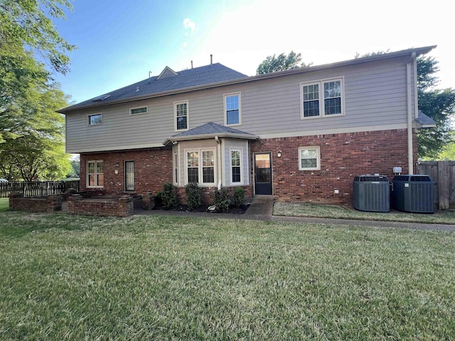 back of property featuring a yard, brick siding, cooling unit, and fence