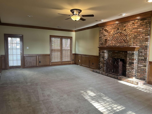unfurnished living room with carpet flooring, ceiling fan, a wainscoted wall, and ornamental molding
