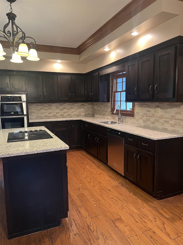 kitchen with crown molding, a sink, light stone counters, stainless steel appliances, and light wood-style flooring
