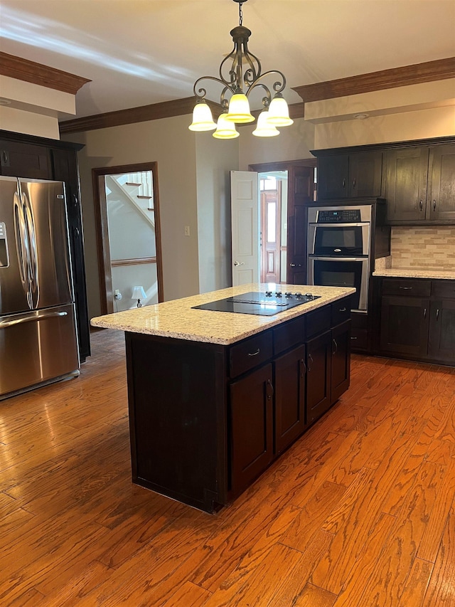 kitchen with stainless steel appliances, ornamental molding, wood finished floors, and tasteful backsplash