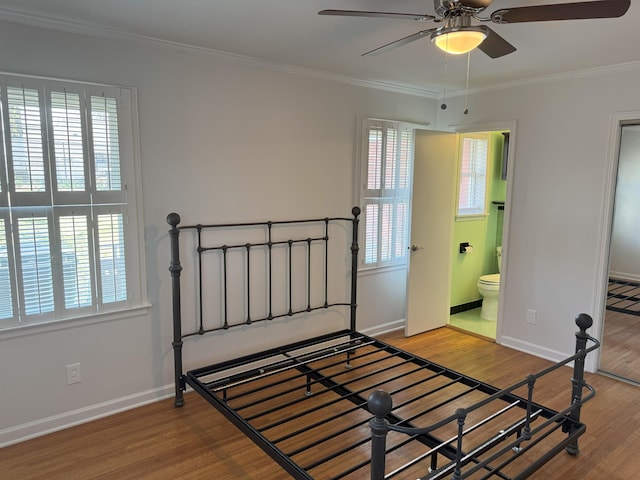 unfurnished bedroom featuring wood finished floors, ornamental molding, baseboards, and ensuite bath