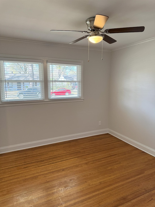 empty room featuring wood finished floors, baseboards, crown molding, and a ceiling fan